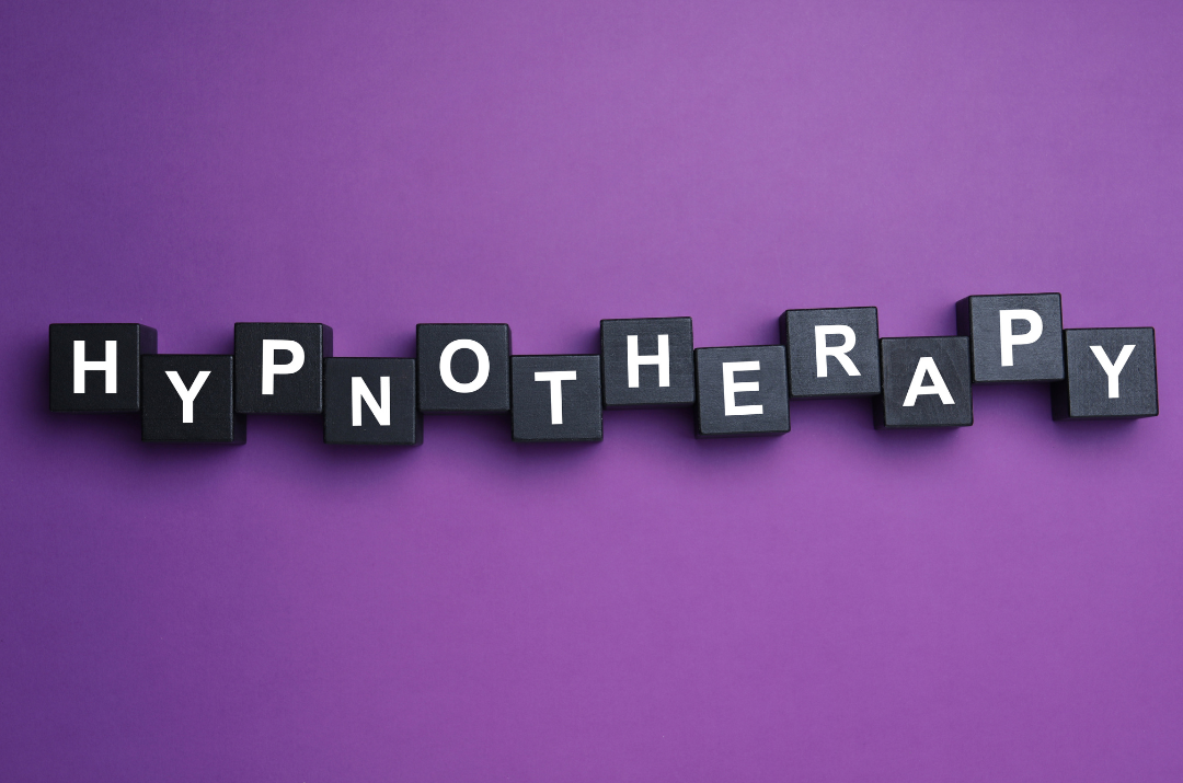 A cadburys chocolate type of purple background with back and white scrabble type of tiles that spell out the word hypnotherapy.